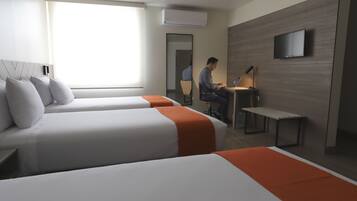 Una habitación de hotel con dos camas, un escritorio, una silla, un televisor y un equipo de aire acondicionado.