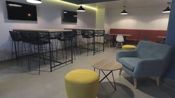 A modern lounge area with a bar, seating, and a flat-screen TV.