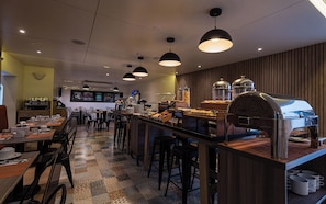 Un caffè moderno con un bancone centrale, zona salotto e angolo caffè.