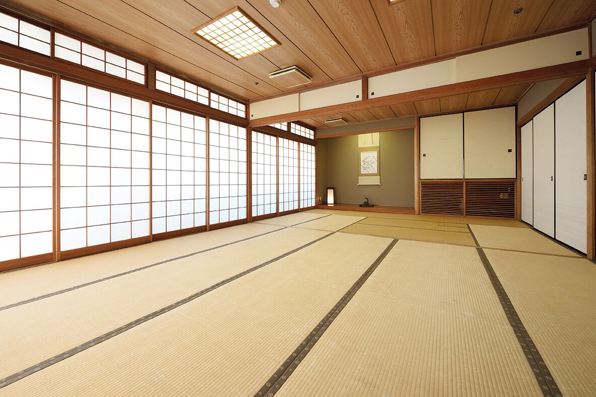 A traditional Japanese room with tatami flooring, sliding doors, and a wooden ceiling.