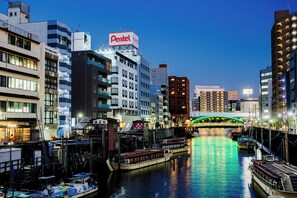 A cityscape with a river, boats, and buildings including a hotel with a sign. - Tokyo Asakusabashi Belmont Hotel (Tokyo)