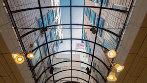 A glass ceiling with hanging lights and a view of buildings outside.