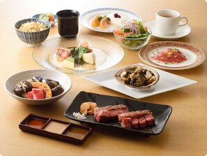 A variety of dishes including sushi, sashimi, and a steak, arranged on a wooden table. - Tokyo Asakusabashi Belmont Hotel (Tokyo)