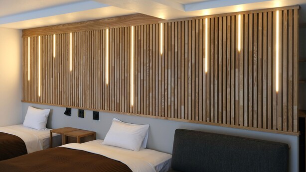 A modern hotel room with a large wooden panel wall, a bed, a small table, and a chair.