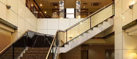 Un vestíbulo amplio con una imponente escalera, zonas de estar confortables y un alto techo con luz natural.