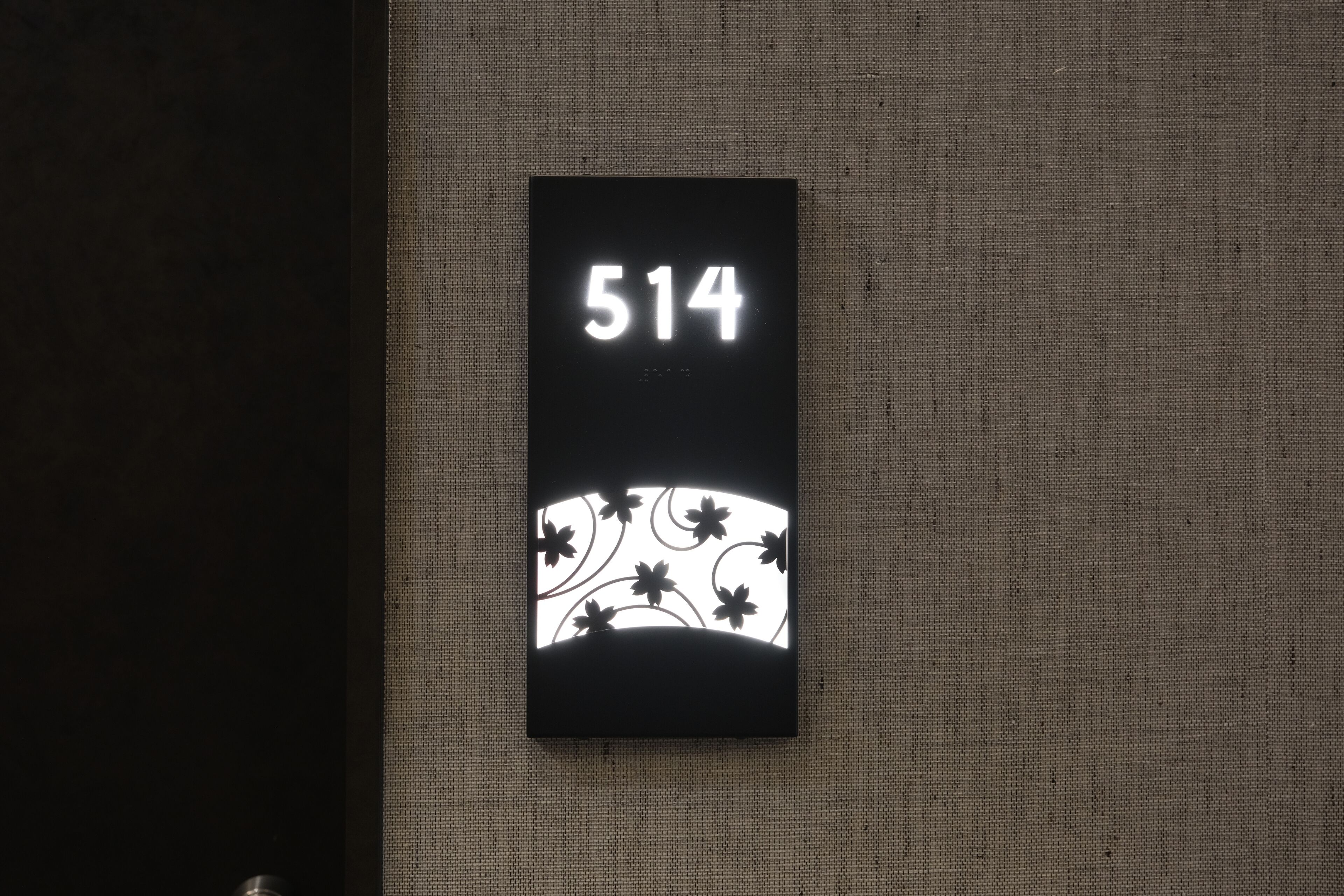 Un letrero negro con el número 514 sobre una pared con textura.