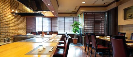 A restaurant with a long wooden table, brick walls, and sliding doors.