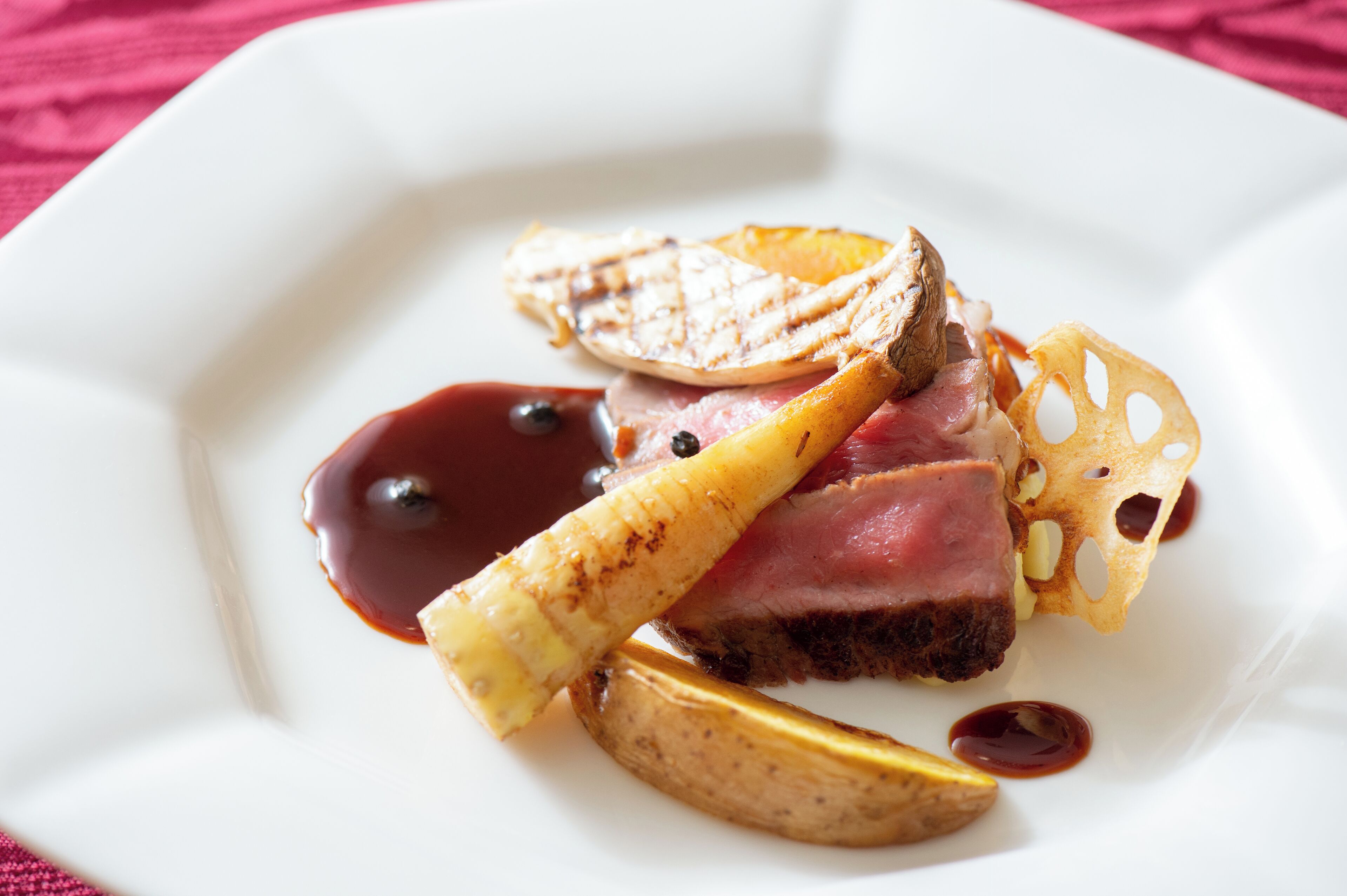 A plate with a piece of meat, grilled potato slices, and a decorative item.