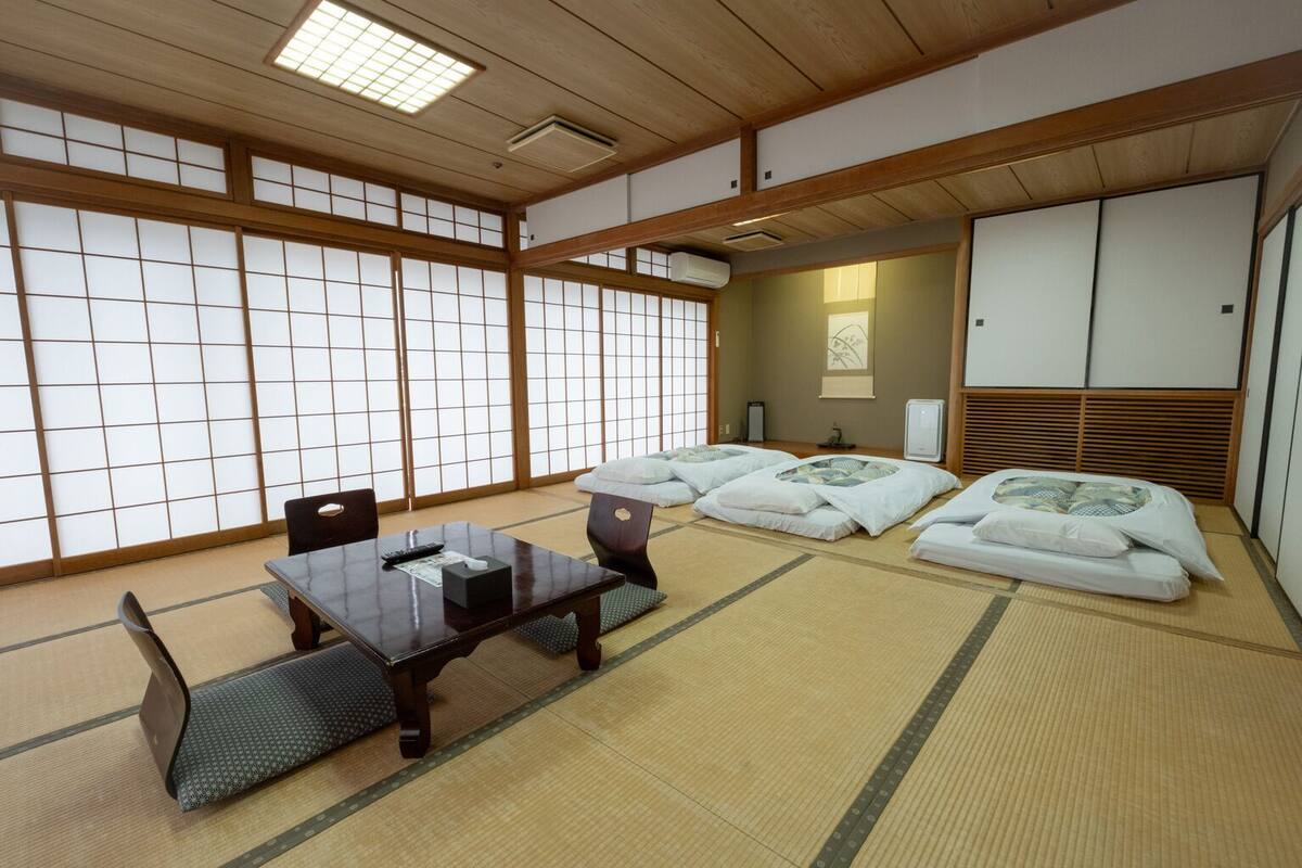 A tatami room with a low table, cushions, and sliding doors.