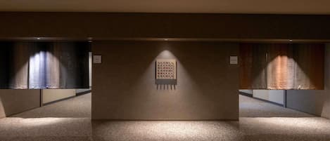 A hallway with carpeted floors and walls, featuring two signs labeled "Men" and "Women" indicating restroom locations.