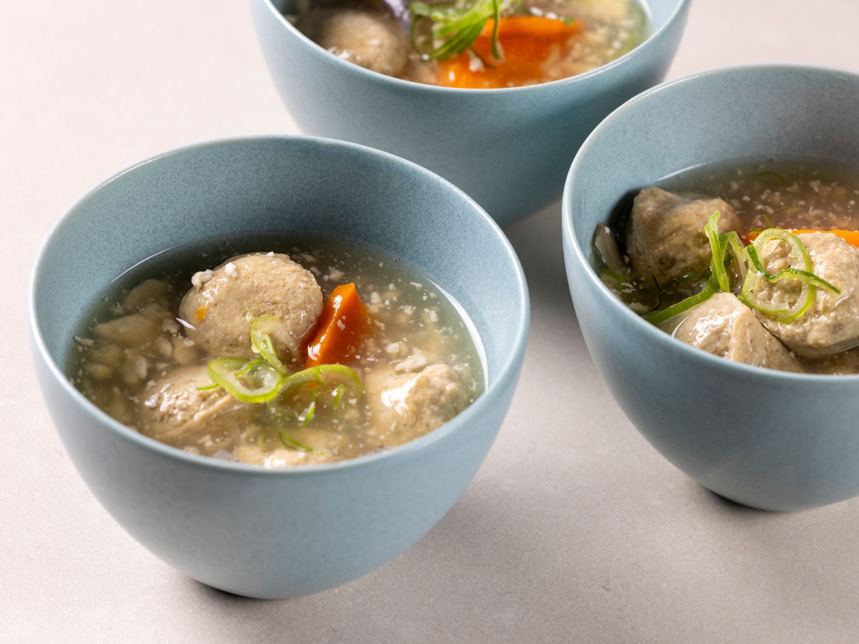 Drei Schüsseln Suppe mit Fleischbällchen und Gemüse.