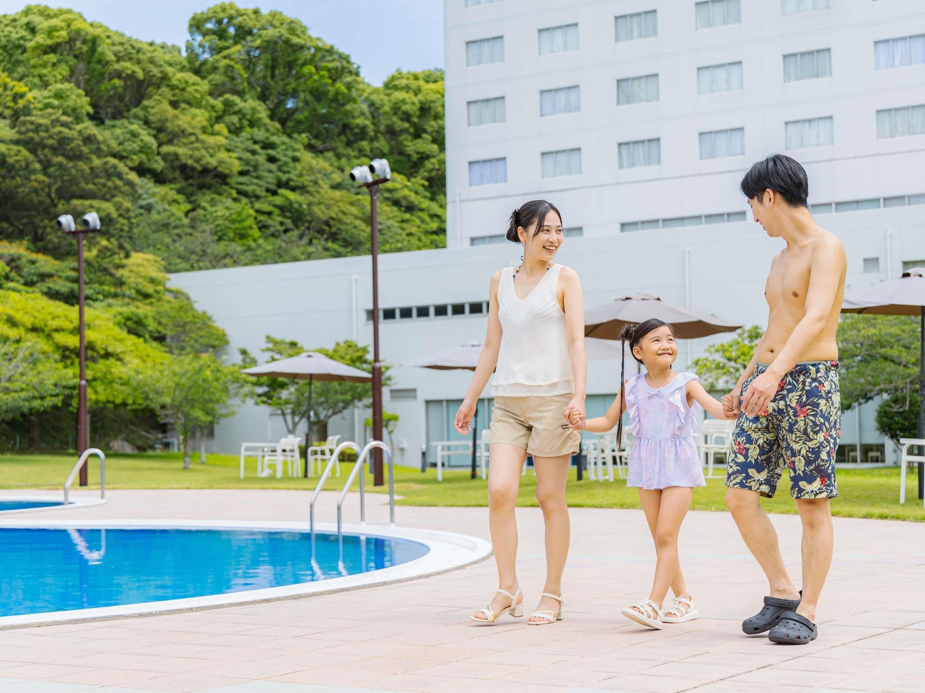 A swimming pool with a clear blue water surface, surrounded by a paved walkway.