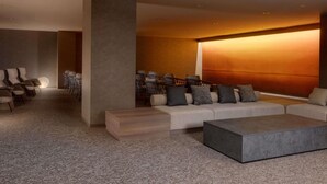 A modern living room with a sectional sofa, a coffee table, and a dining area with chairs. - Mercure Fukuoka Munakata Resort & Spa (Munakata)