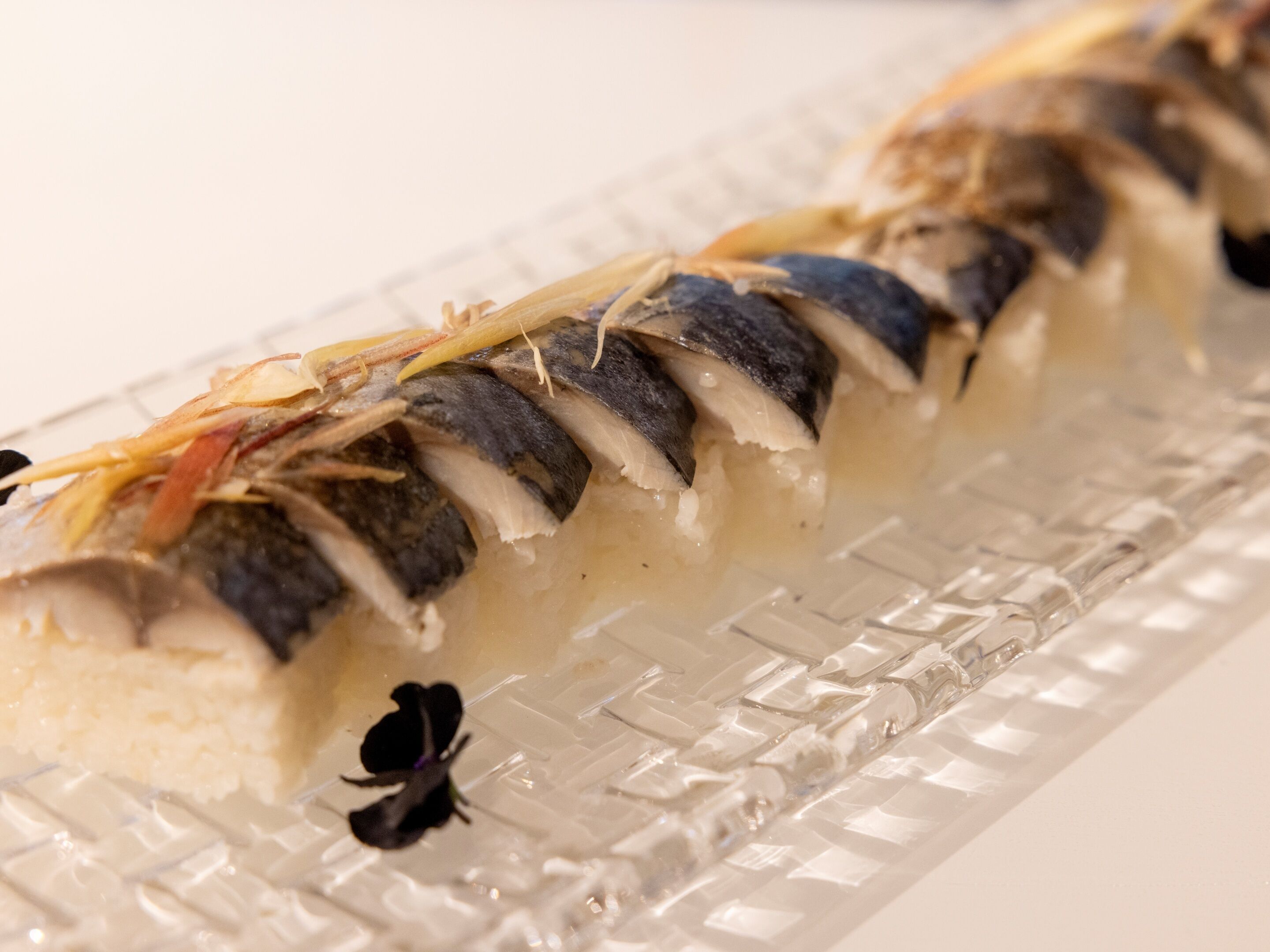 A dish of fish with vegetables on a clear glass plate.
