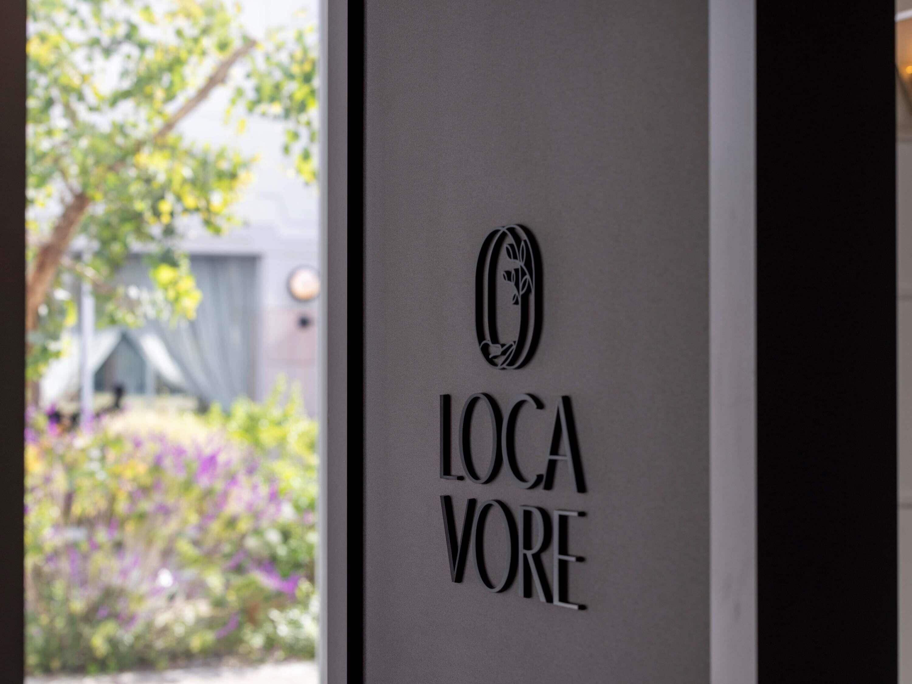 Um letreiro com o texto 'LOCA VORE' e um logotipo acima.