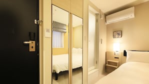 A hotel room with a bed, a wardrobe, a nightstand, and an air conditioning unit. - Hotel Nihonbashi Saibo (Tokyo)