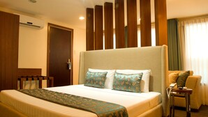 A hotel room with a large bed, a wooden headboard, a bedside table with a phone, and a window with curtains. - El Cielito Hotel (Makati)