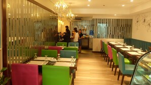 A restaurant with colorful chairs and tables, a chandelier, and a counter area. - El Cielito Hotel (Makati)