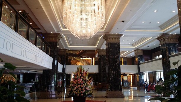 A grand lobby with a large chandelier, marble columns, and a central floral arrangement. - Hotel Presidente Macau (Macau)