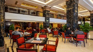 A spacious hotel lobby with multiple dining tables and chairs, large pillars, and a modern interior design. - Hotel Presidente Macau (Macau)