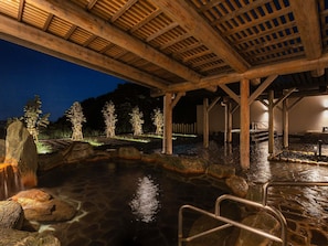 A stone hot spring area with wooden beams overhead, surrounded by trees and a stone pathway. - Grand Mercure Wakayama Minabe Resort & Spa (Minabe)