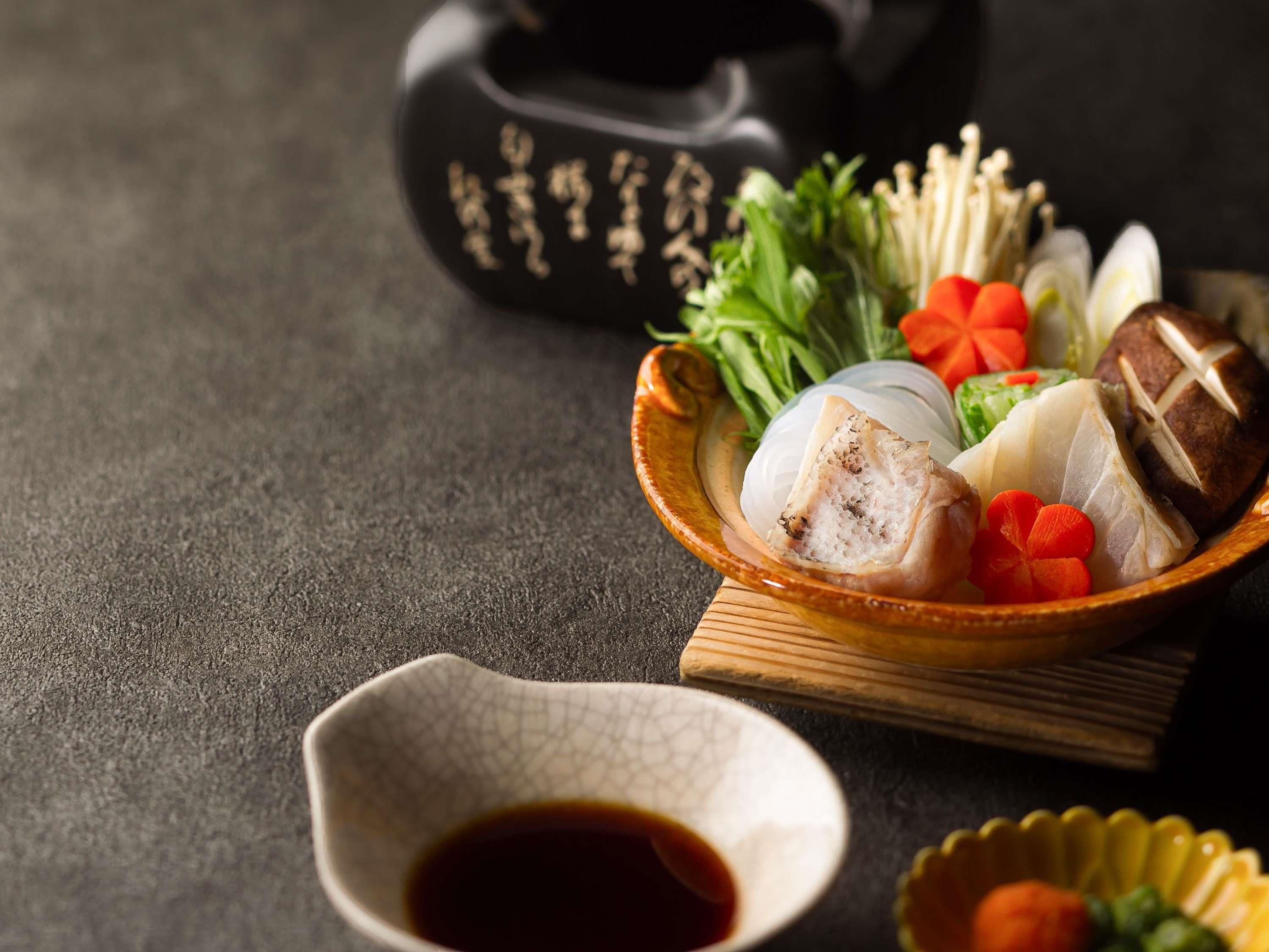 A traditional Japanese meal with fish, vegetables, and a small bowl of soy sauce.