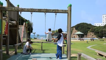 A playground with swings, a climbing structure, and a view of the sea.