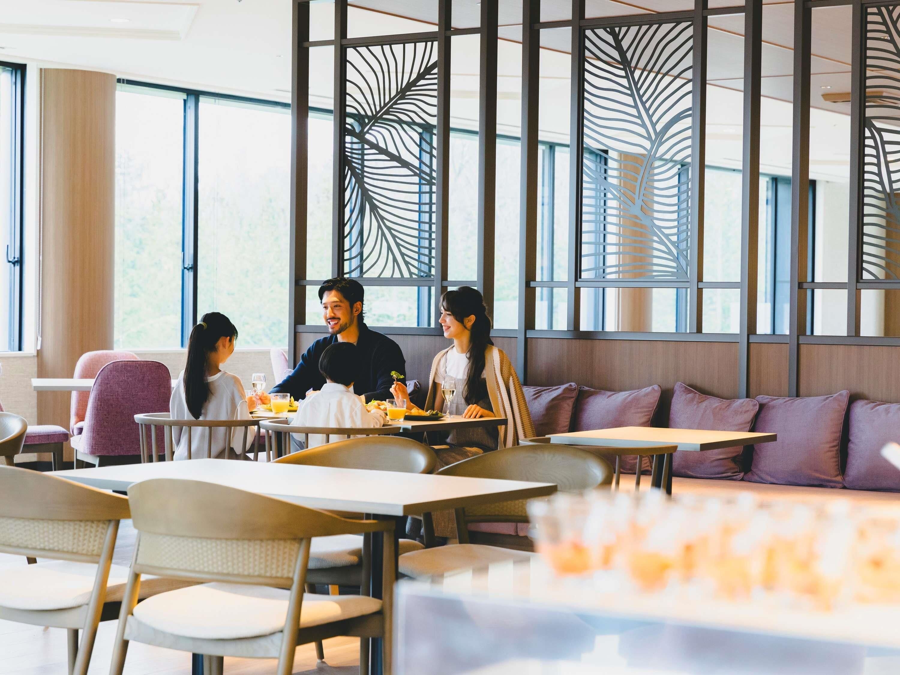 A modern dining area with tables and chairs, large windows, and decorative panels.