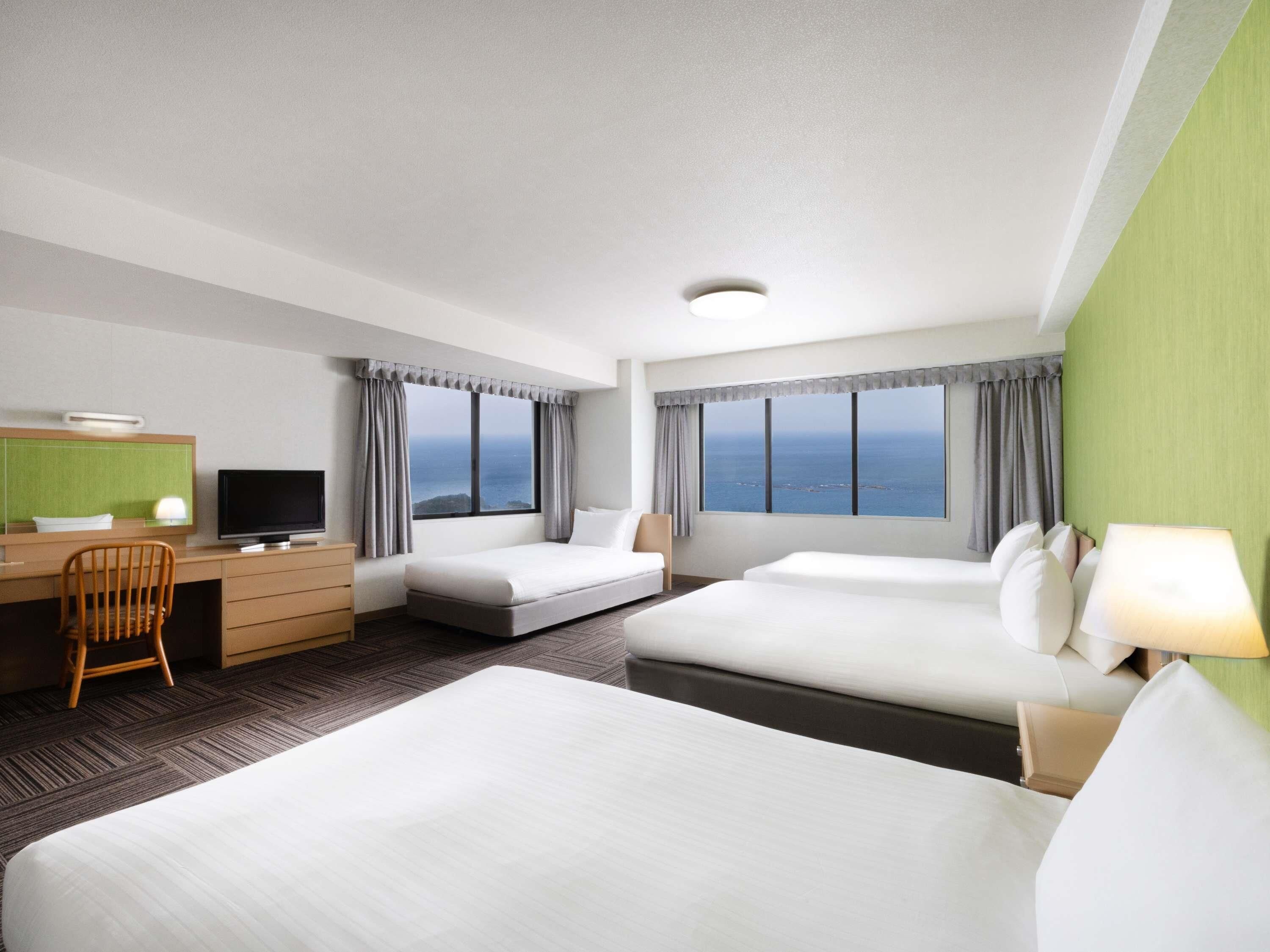 Habitación de hotel con dos camas, un escritorio, una silla y un televisor.