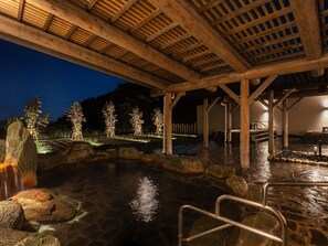 A stone hot spring area with wooden beams overhead, surrounded by trees and a stone pathway. - Grand Mercure Wakayama Minabe Resort & Spa (Minabe)