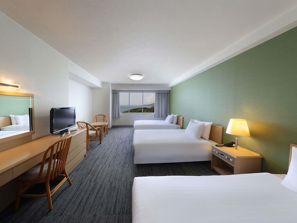 Une chambre d’hôtel avec deux lits, un bureau avec une télévision, une chaise, une lampe et une fenêtre donnant sur un paysage agréable.