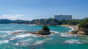 Um hotel à beira-mar com vista para águas azul-turquesa e formações rochosas.