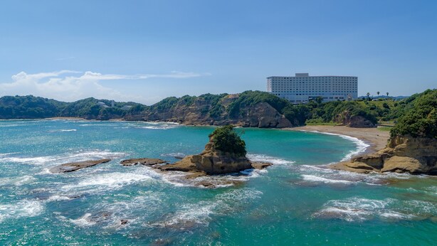 Un hotel sul lungomare con vista su acque turchesi e promontori rocciosi.