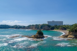 Un hôtel en bord de mer offrant une vue sur des eaux turquoise et des formations rocheuses.