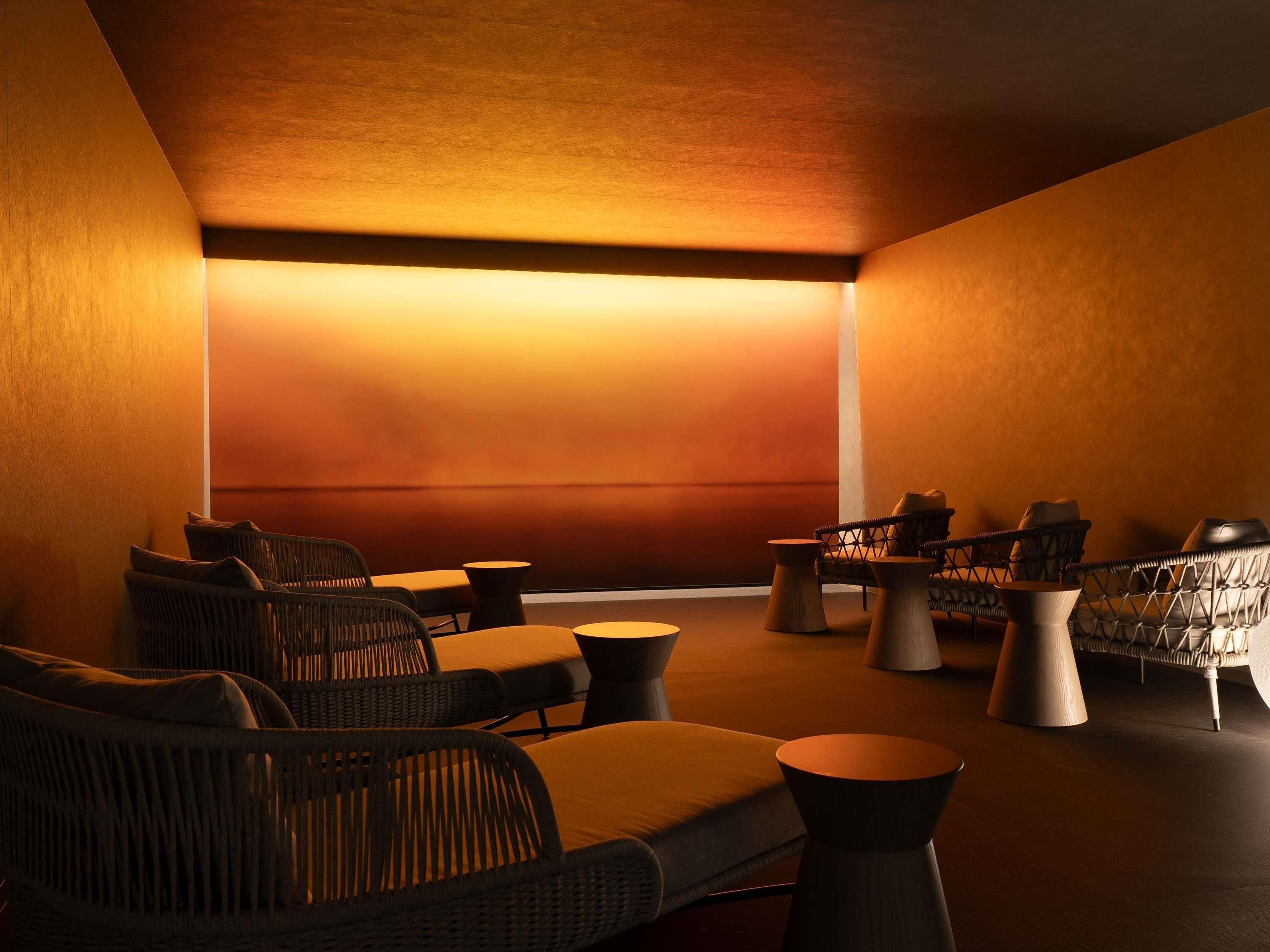 A dimly lit lounge area with wicker furniture and round tables.