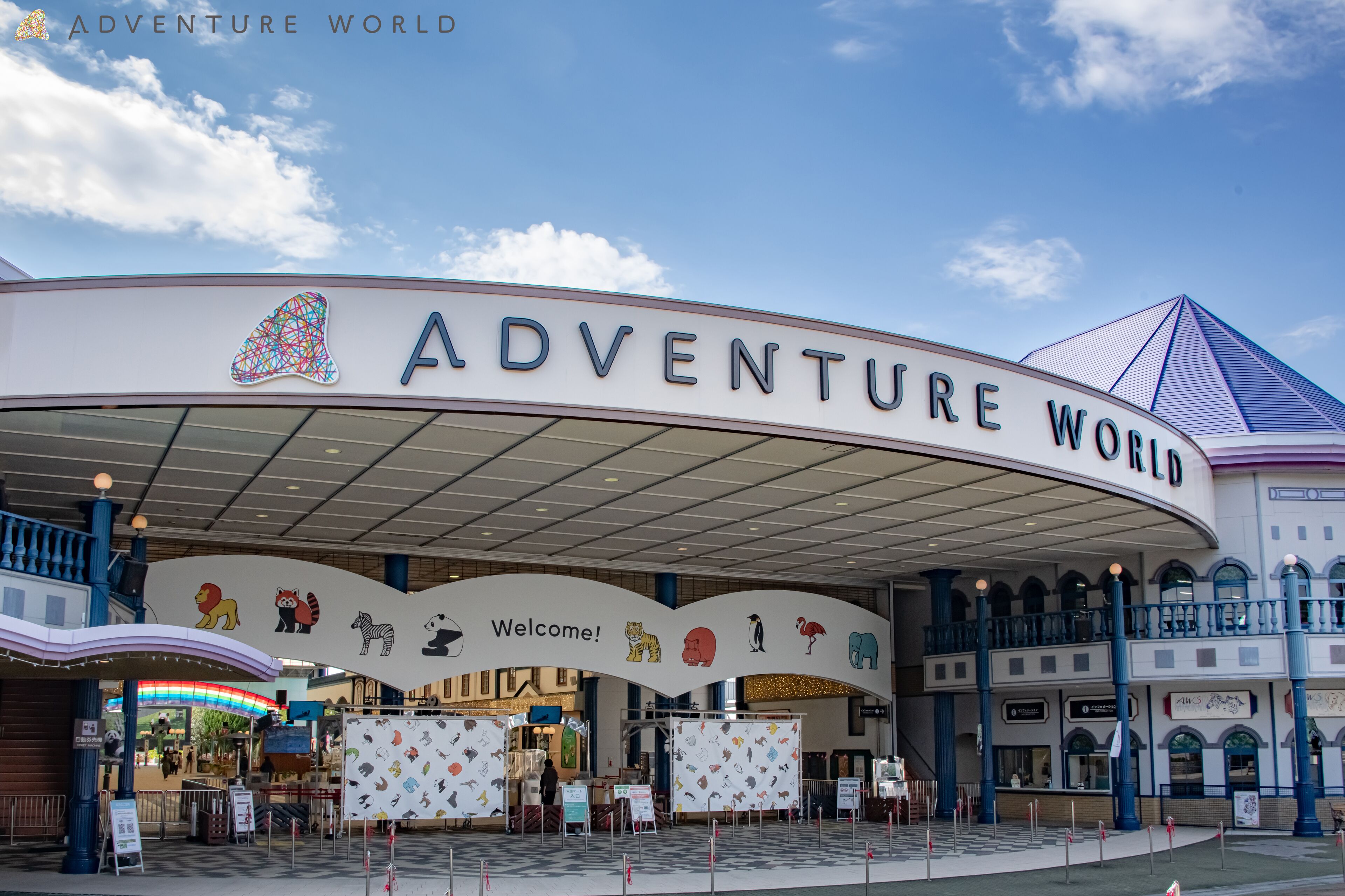 The exterior of Adventure World with a large entrance arch displaying various animal icons and the words "Welcome!".