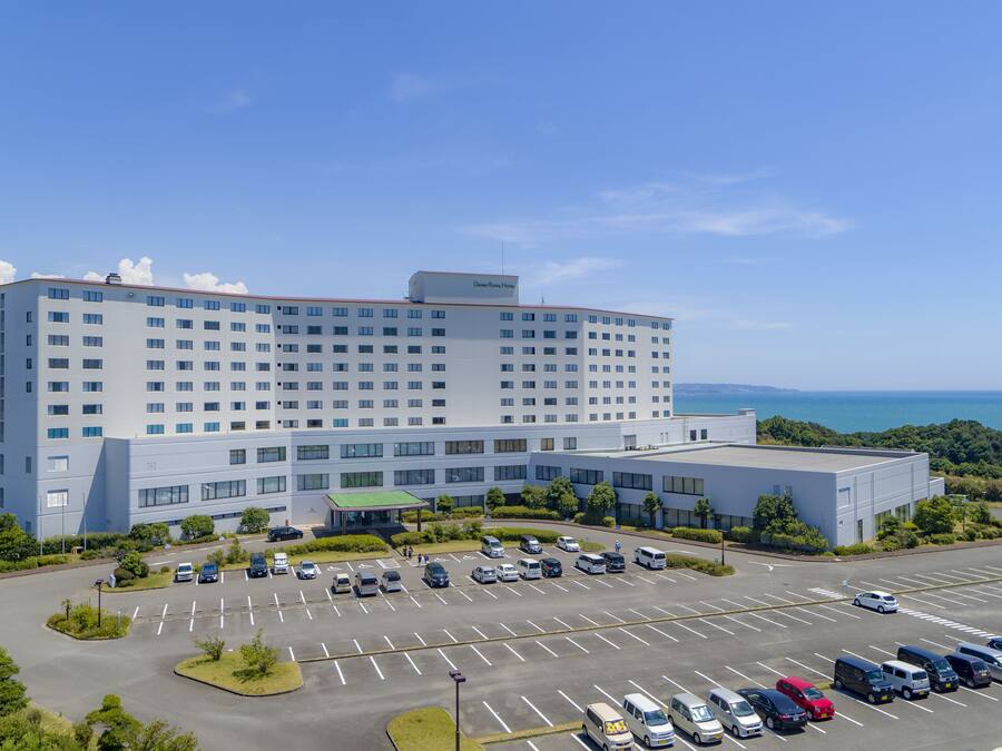 A large hotel with multiple floors and a parking lot in front.