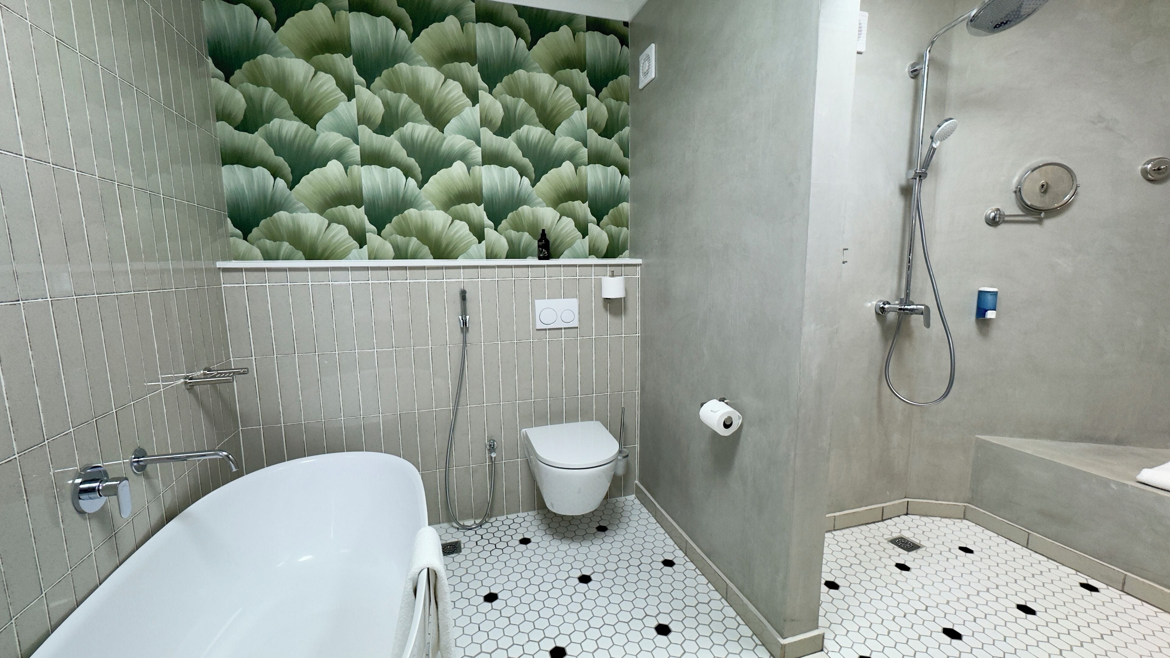 A bathroom with a white bathtub, a toilet, and a shower area.