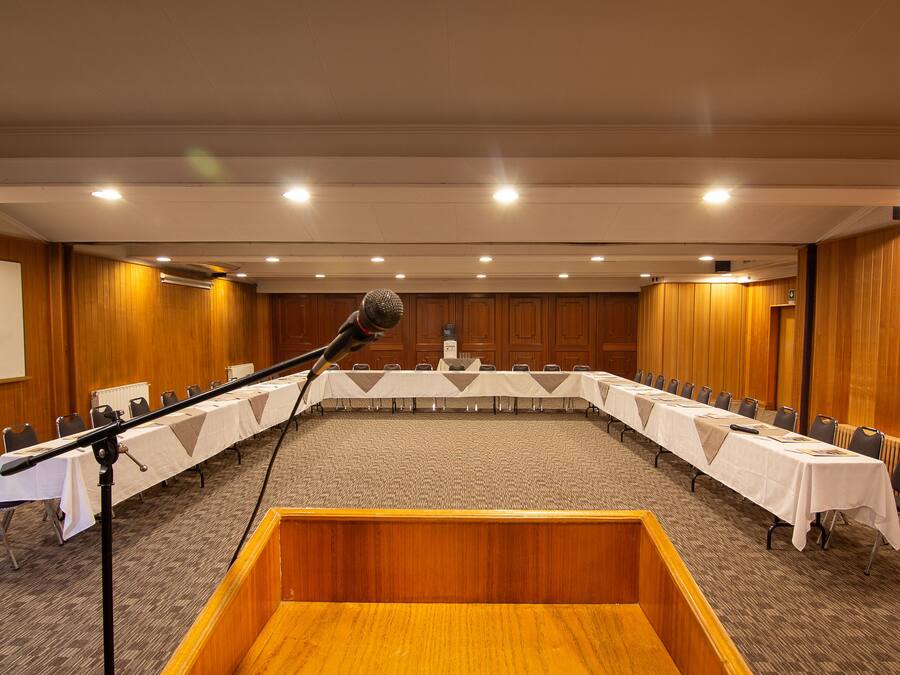 A conference room with a long table, chairs, a podium, and a whiteboard.