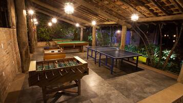 An indoor recreational area with a foosball table, ping pong table, and pool table.