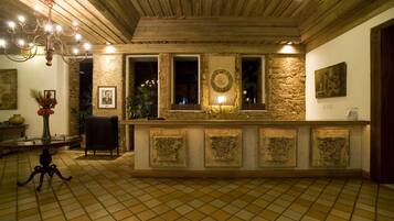 A reception area with a stone wall, a chandelier, and a tiled floor.