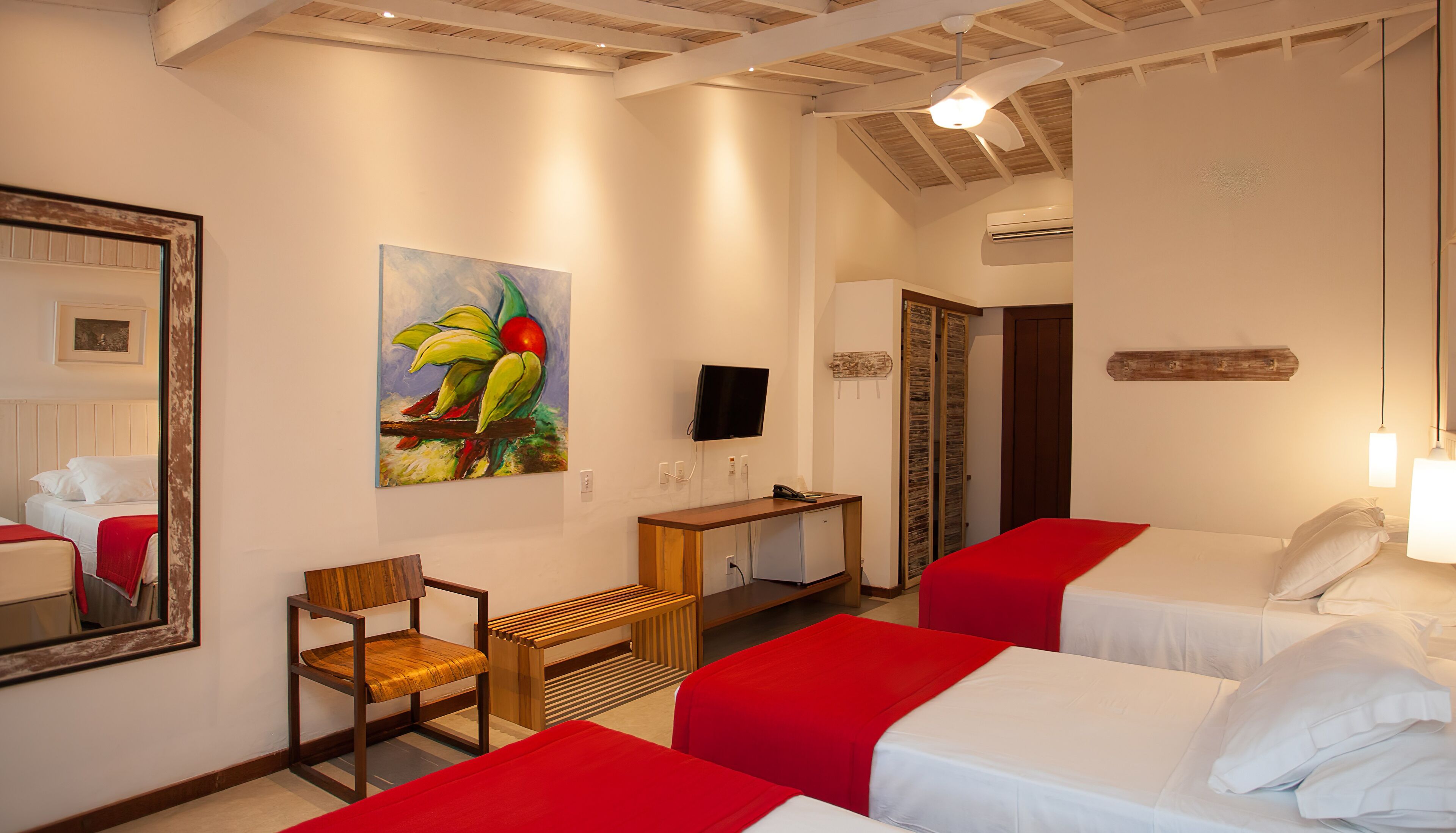 Habitación de hotel con dos camas, un escritorio, una silla, un cuadro, un televisor y un equipo de aire acondicionado.