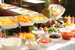 Een buffet met diverse soorten eten, zoals fruit, groenten en sauzen.