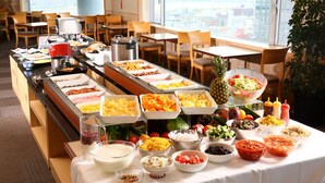 Een buffet met diverse gerechten en een stadszicht door grote ramen.