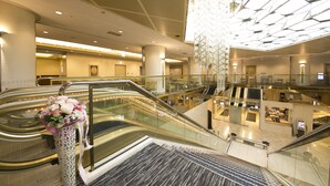 Een binnentuin met roltrappen, een glazen balustrade en een decoratieve bloemstelling.