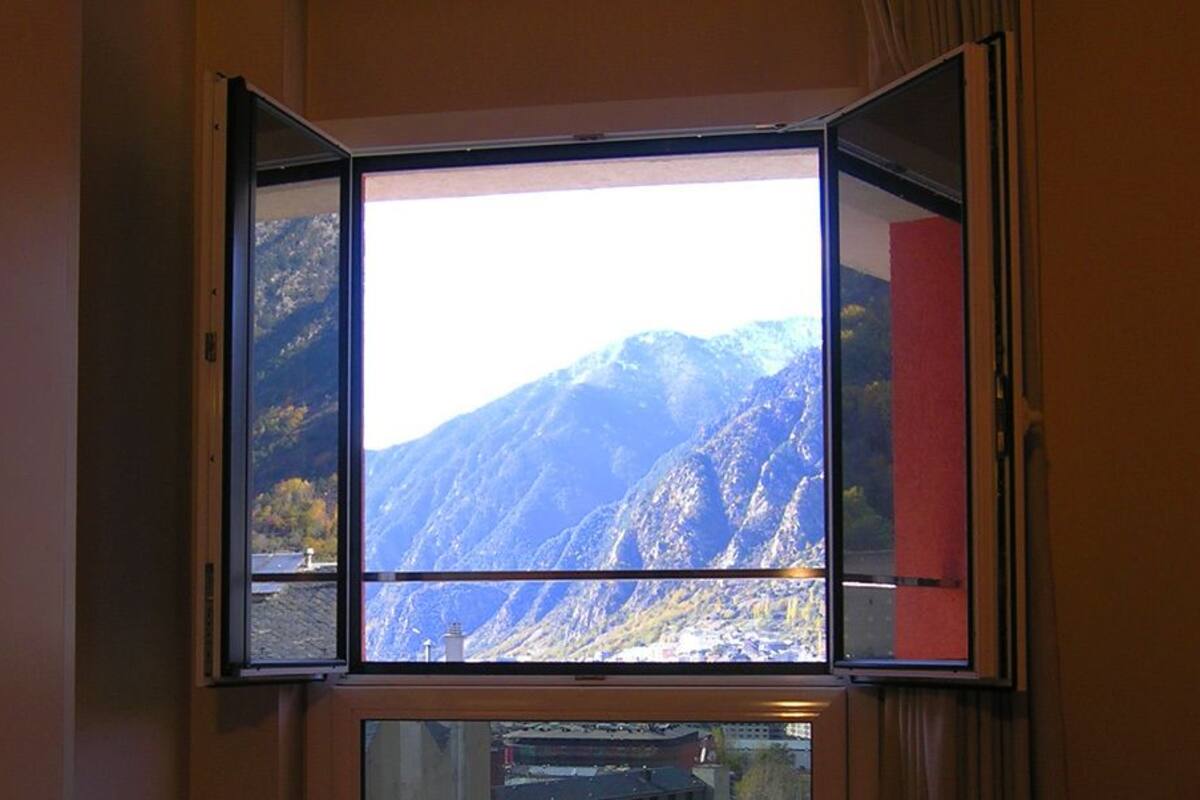 Quarto com vista para montanhas através de uma janela.
