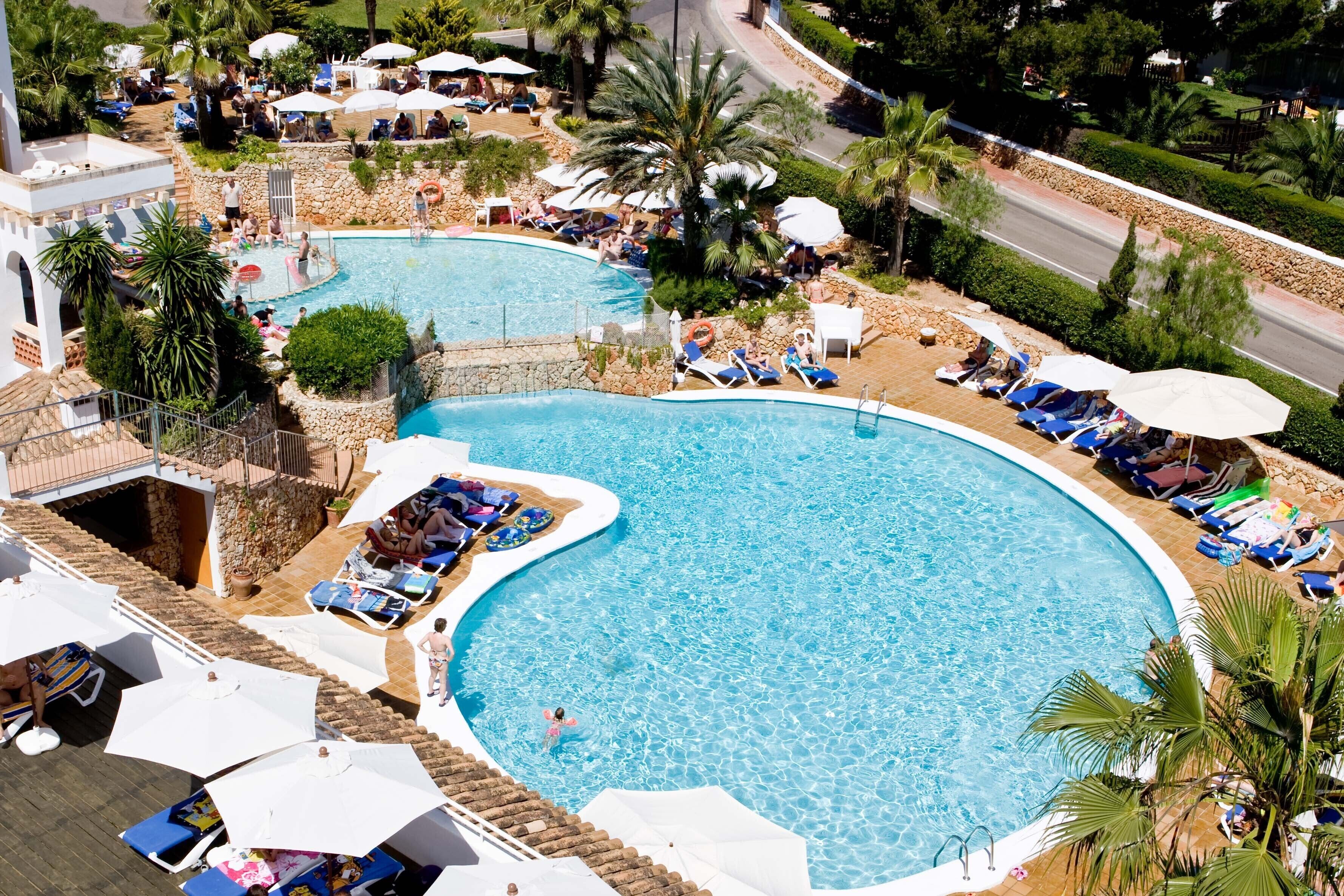 Una piscina al aire libre, sombrillas, tumbonas