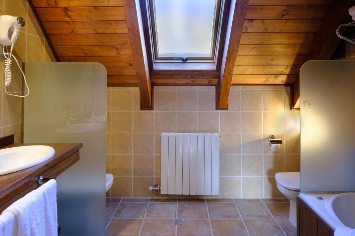 Un baño con tragaluz, techo de madera y radiador blanco.