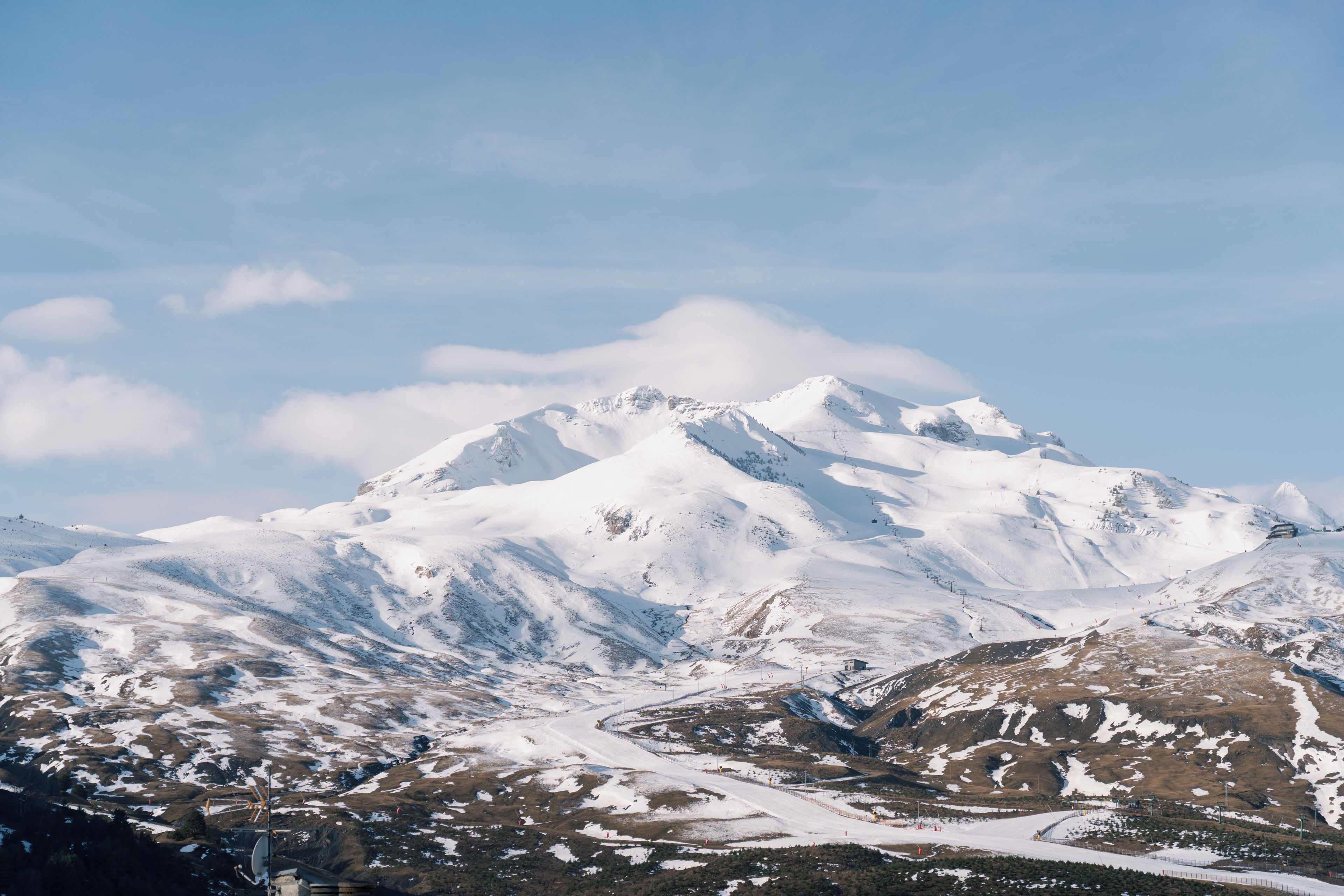 A snow-covered mountain with a ski slope and a small cabin.