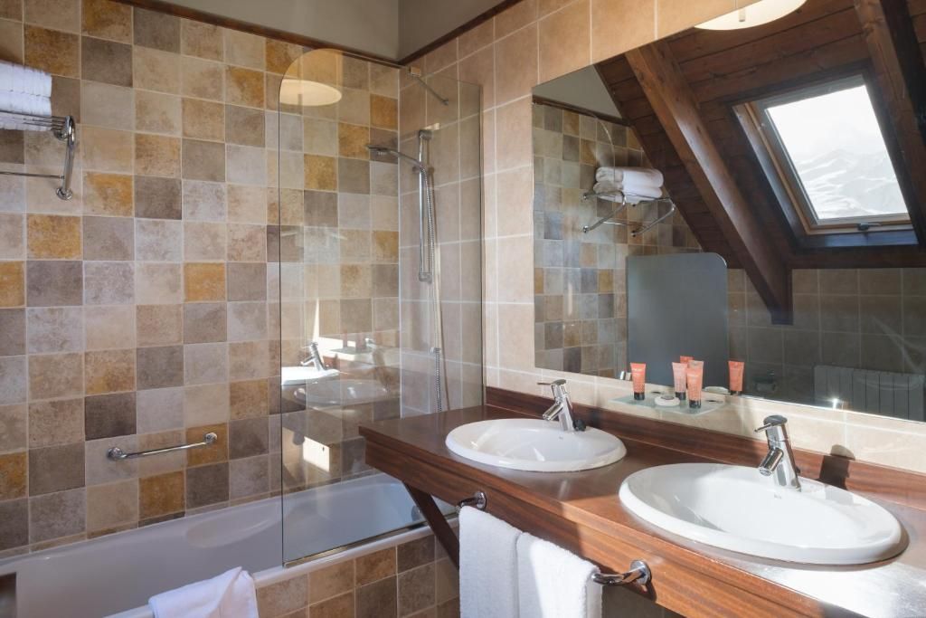 Un baño con dos lavamanos, una ducha y un tragaluz.